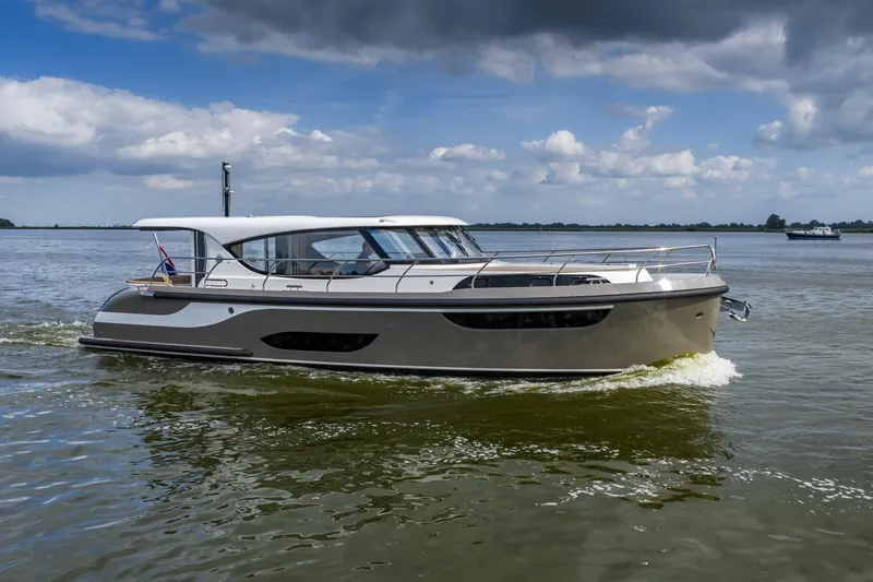  Yacht Photos Pics 2024 Vripack 42 Open Kuip yacht cruising on a calm lake under cloudy skies.