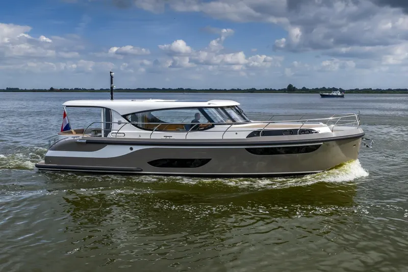  Yacht Photos Pics 2024 Vripack 42 Open Kuip yacht cruising on a calm lake under a cloudy sky.
