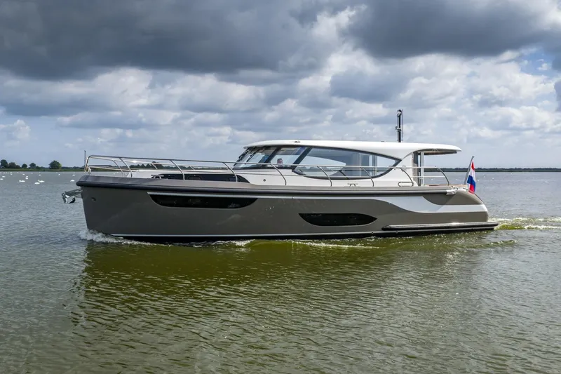  Yacht Photos Pics 2024 Vripack 42 Open Kuip yacht cruising on a calm lake under cloudy skies.