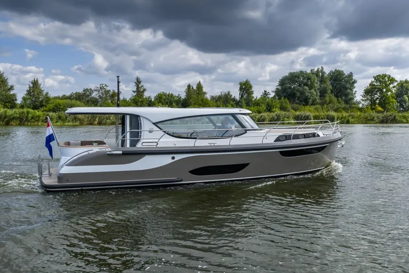  Yacht Photos Pics 2024 Vripack 42 Open Kuip yacht cruising on a serene river under cloudy skies.