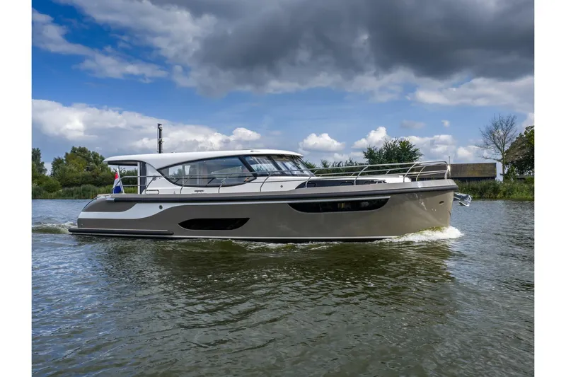  Yacht Photos Pics 2024 Vripack 42 Open Kuip yacht cruising on a serene waterway under cloudy skies.