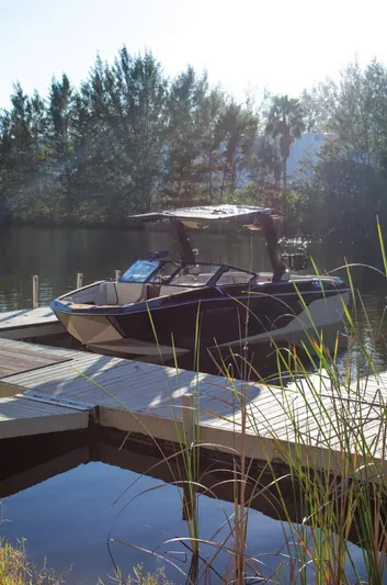  Yacht Photos Pics 2025 Nautique Super Air Nautique G25 docked on a serene lake with trees in the background.