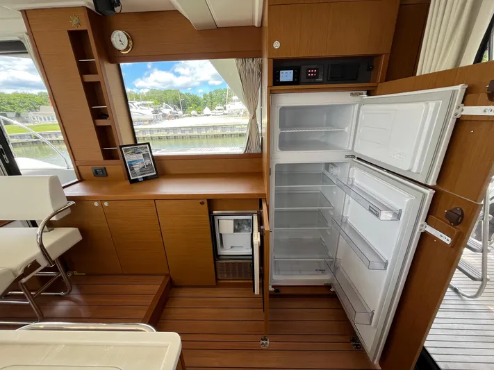  Yacht Photos Pics Interior of 2023 Beneteau Swift Trawler 41 Fly with open fridge and wooden cabinetry.