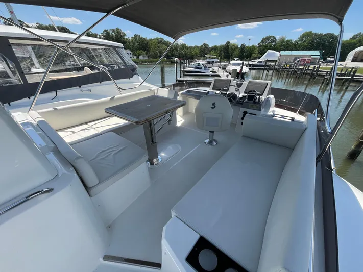  Yacht Photos Pics 2023 Beneteau Swift Trawler 41 Fly, spacious flybridge with seating and table, docked at marina.