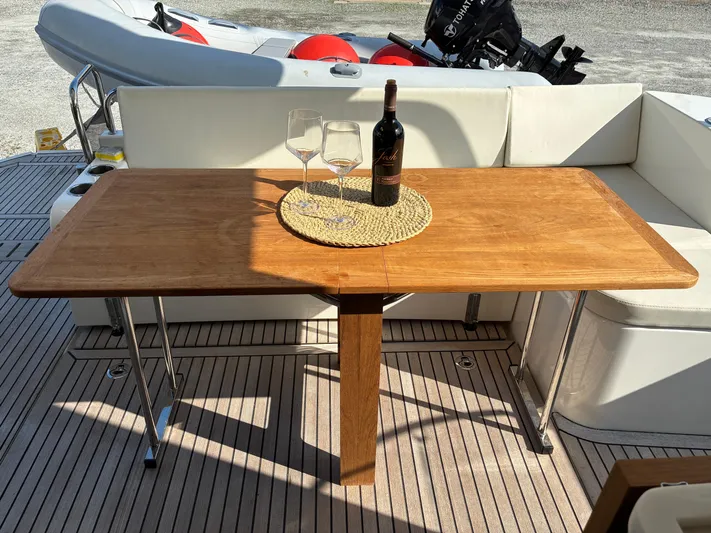  Yacht Photos Pics Elegant wooden table on 2023 Beneteau Swift Trawler 41 Fly, featuring wine and glasses.