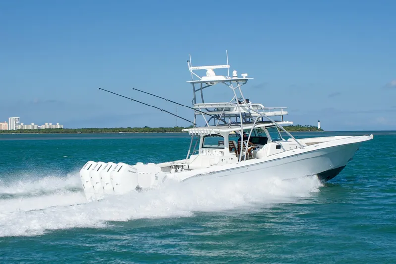  Yacht Photos Pics 2023 HCB 53 Sue&ntilde;os boat cruising on blue ocean with cityscape and lighthouse in background.