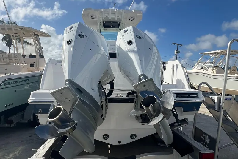 252-449 Yacht Photos Pics 2025 Blackfin 252 CC boat with dual outboard engines, docked under a clear sky.