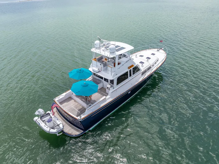 Alacrity Yacht Photos Pics 2008 Lyman-Morse Flybridge 62' yacht on calm water, featuring blue umbrellas.
