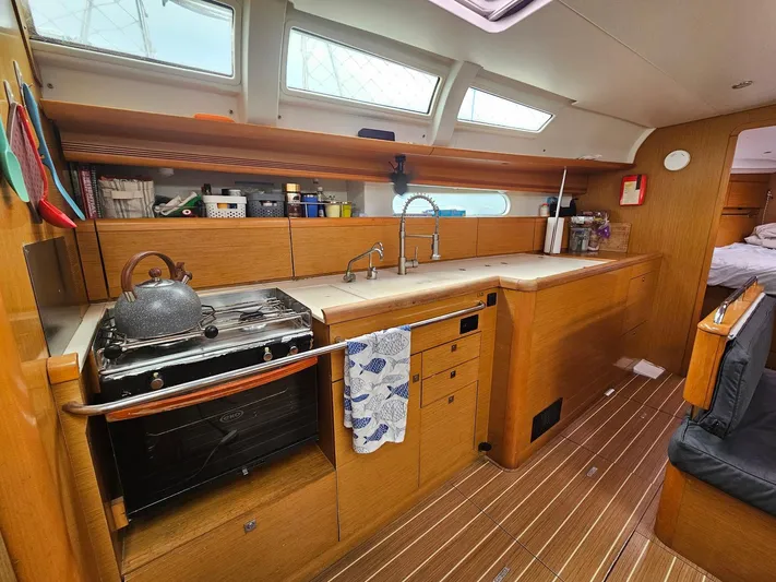 Helix Yacht Photos Pics Interior of 2011 Jeanneau 44i sailboat kitchen with stove, sink, and wooden cabinetry.