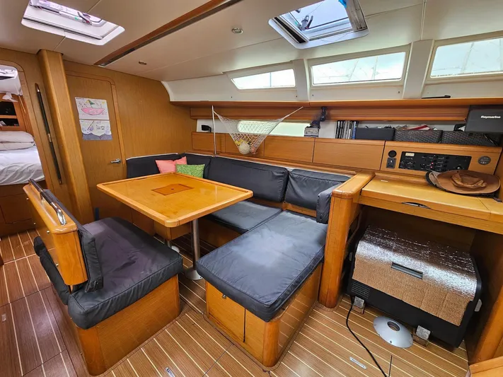Helix Yacht Photos Pics Interior of 2011 Jeanneau 44i sailboat with wooden furnishings and cozy seating area.