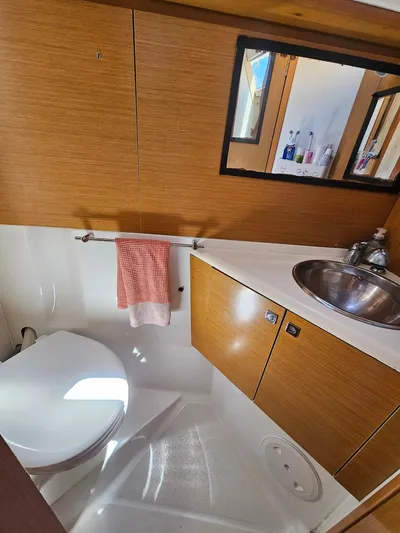 Helix Yacht Photos Pics 2011 Jeanneau 44i yacht bathroom with wooden cabinetry, sink, and toilet.