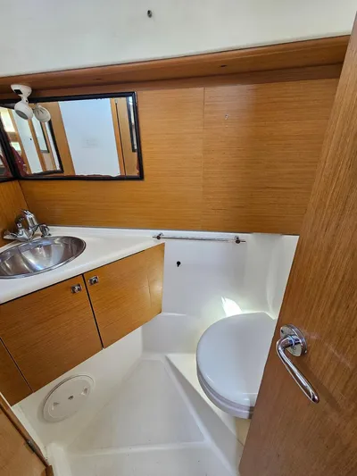 Helix Yacht Photos Pics 2011 Jeanneau 44i yacht bathroom with sink, mirror, and wooden cabinetry.