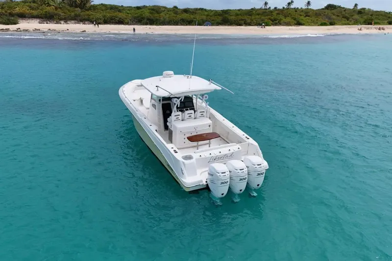  Yacht Photos Pics 2010 Boston Whaler 370 Outrage boat on turquoise water near a sandy beach.