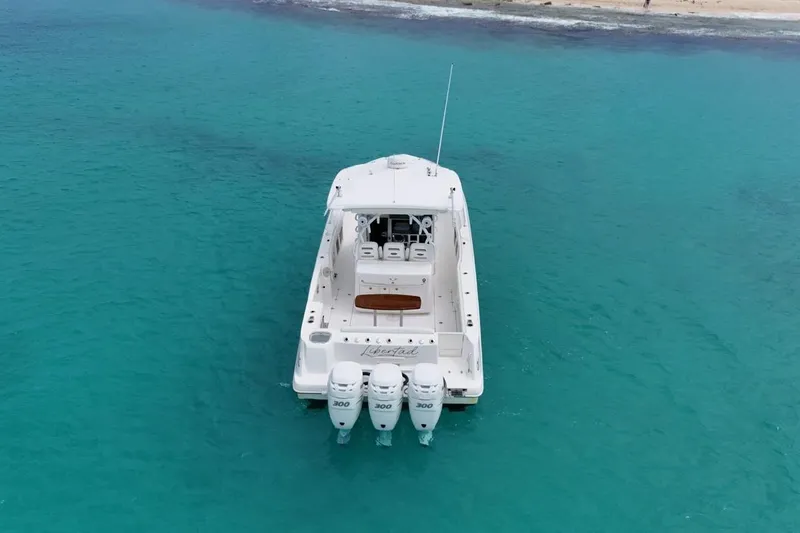  Yacht Photos Pics Boston Whaler 370 Outrage 2010 boat on turquoise water near sandy shore.