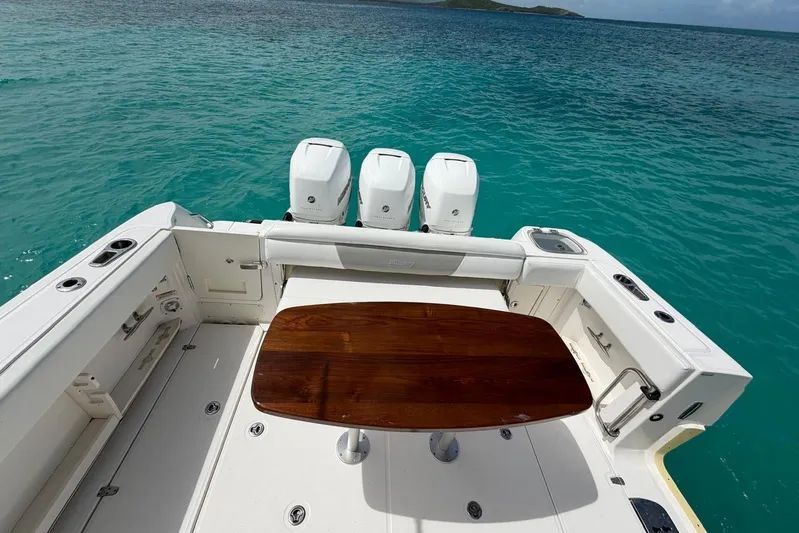  Yacht Photos Pics 2010 Boston Whaler 370 Outrage boat with triple engines and wooden table on turquoise water.