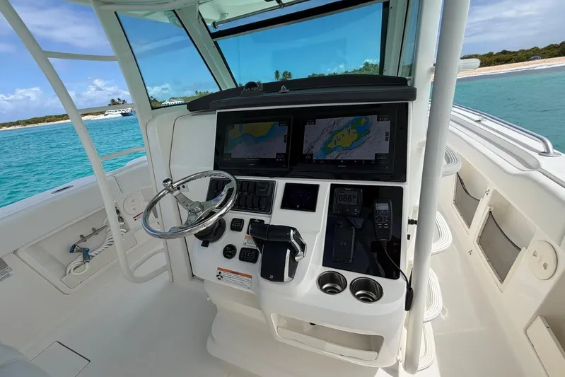  Yacht Photos Pics Boston Whaler 370 Outrage 2010 helm with navigation screens and steering wheel, ocean backdrop.