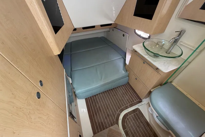  Yacht Photos Pics Interior cabin of 2010 Boston Whaler 370 Outrage with bed, sink, and wooden cabinetry.