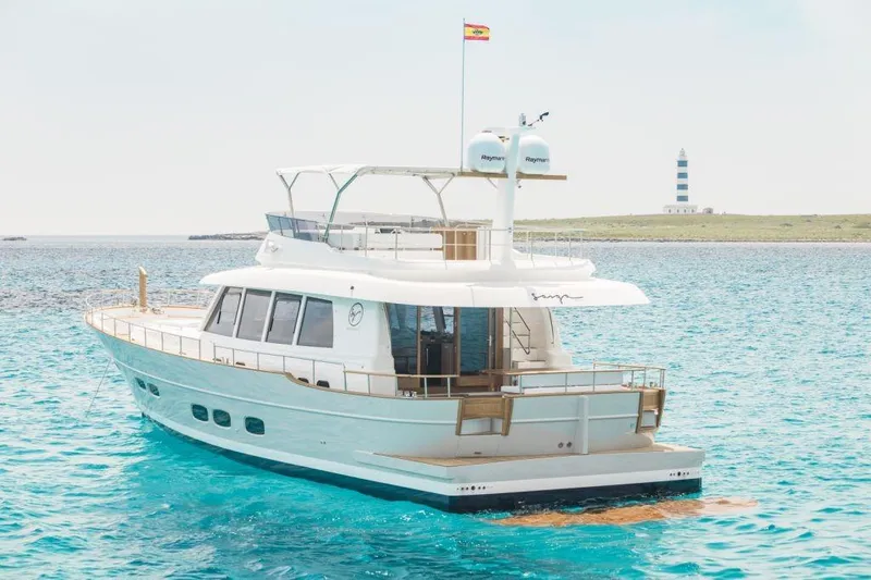 Sasga Yachts 68 Flybridge Yacht Photos Pics 2026 Sasga Yachts Menorquin 68 FB cruising in clear blue waters near a lighthouse.