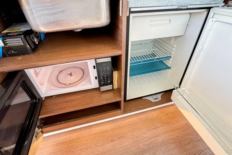  Yacht Photos Pics Kitchen area in 2022 Beneteau Antares 11 with microwave and open fridge.