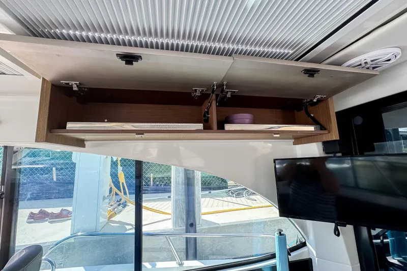  Yacht Photos Pics Open cabinet in 2022 Beneteau Antares 11 boat interior with TV and window view.