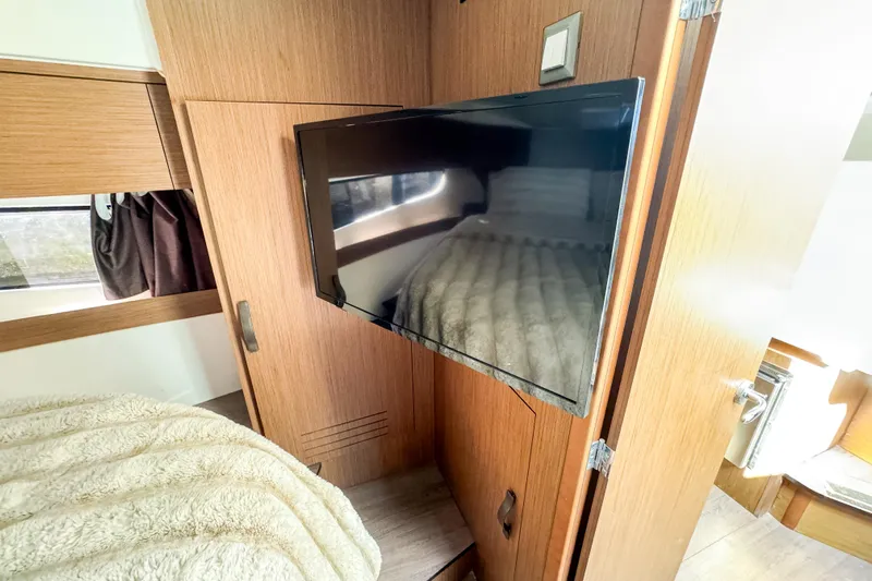  Yacht Photos Pics 2022 Beneteau Antares 11 cabin interior with TV and cozy bedding.