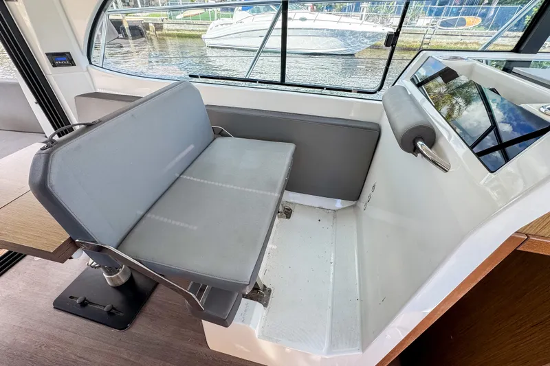  Yacht Photos Pics Interior seating area of 2022 Beneteau Antares 11 boat, featuring a cushioned bench.