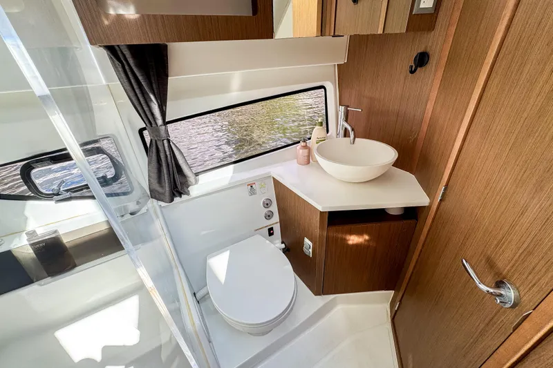  Yacht Photos Pics Modern bathroom in 2022 Beneteau Antares 11 yacht with sleek fixtures and wood accents.