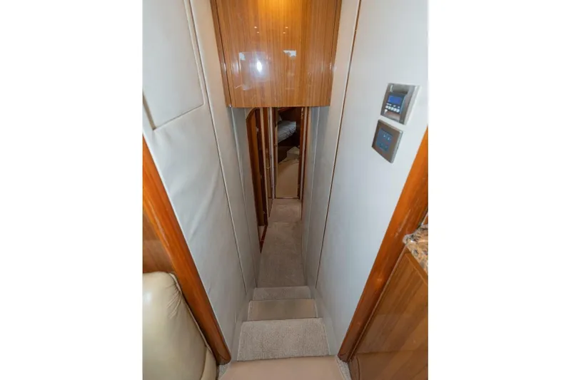 Stay Salty Yacht Photos Pics Narrow hallway inside 2009 Viking 50 Convertible yacht with wooden paneling and carpeted steps.