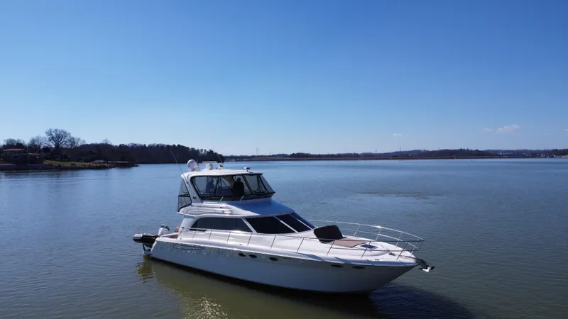  Yacht Photos Pics 2001 Sea Ray 480 Sedan Bridge yacht on calm lake under clear blue sky.