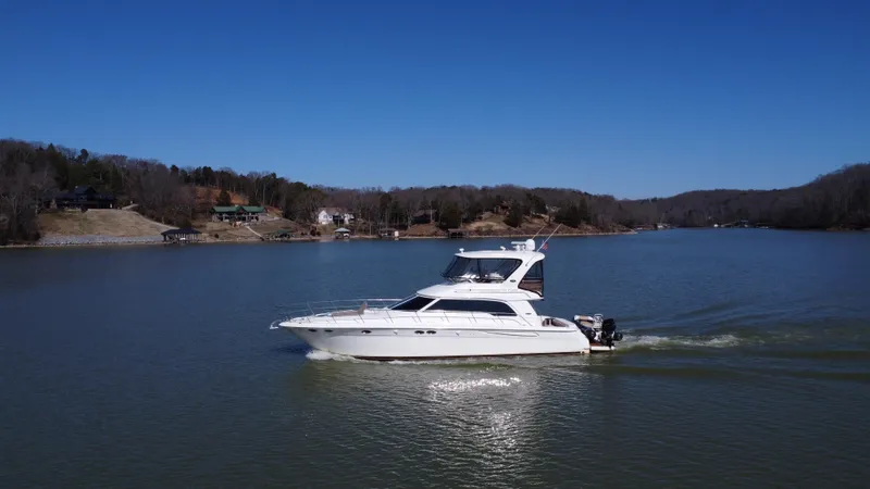  Yacht Photos Pics 2001 Sea Ray 480 Sedan Bridge cruising on a serene lake under a clear blue sky.