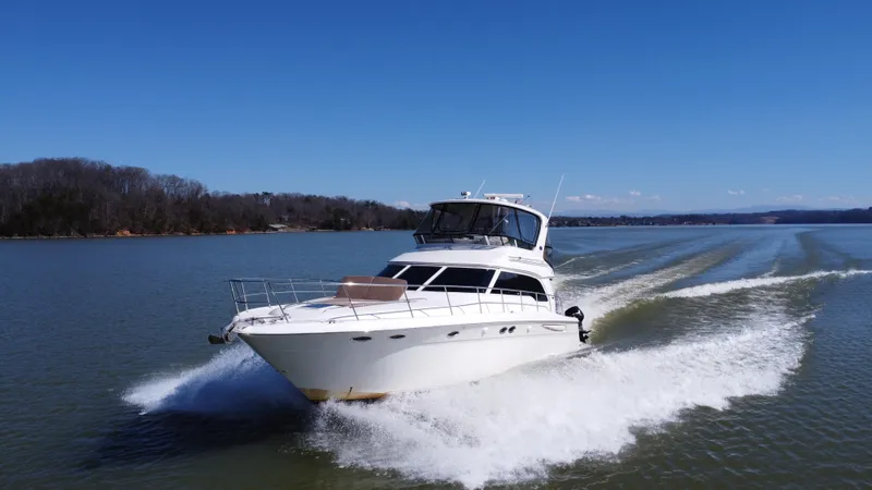 Yacht Photos Pics 2001 Sea Ray 480 Sedan Bridge cruising on a calm lake under clear blue skies.