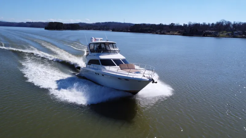  Yacht Photos Pics 2001 Sea Ray 480 Sedan Bridge cruising on a serene lake under clear skies.