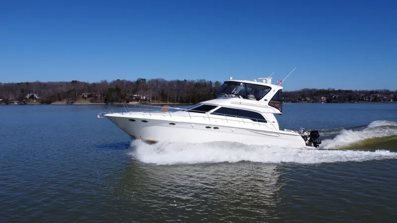  Yacht Photos Pics 2001 Sea Ray 480 Sedan Bridge cruising on a calm lake under clear blue skies.