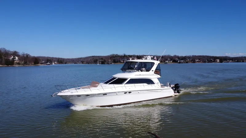  Yacht Photos Pics 2001 Sea Ray 480 Sedan Bridge cruising on a calm lake under clear blue skies.