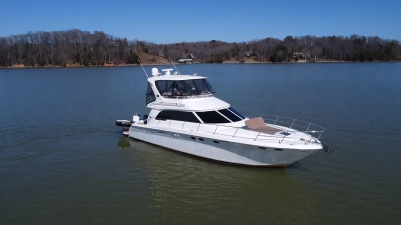  Yacht Photos Pics 2001 Sea Ray 480 Sedan Bridge yacht on a calm lake with wooded shoreline.