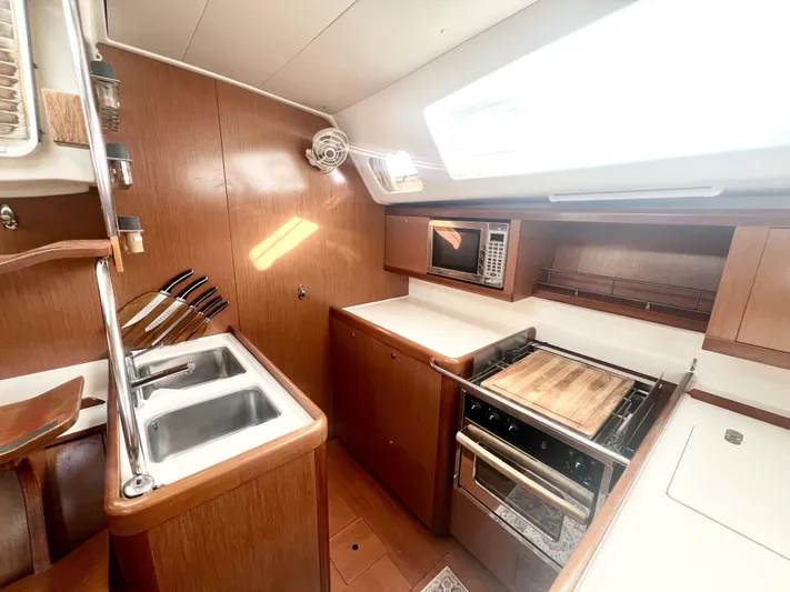 Island Time Ll Yacht Photos Pics 2008 Beneteau 46 yacht kitchen with wooden cabinetry, sink, stove, and microwave.