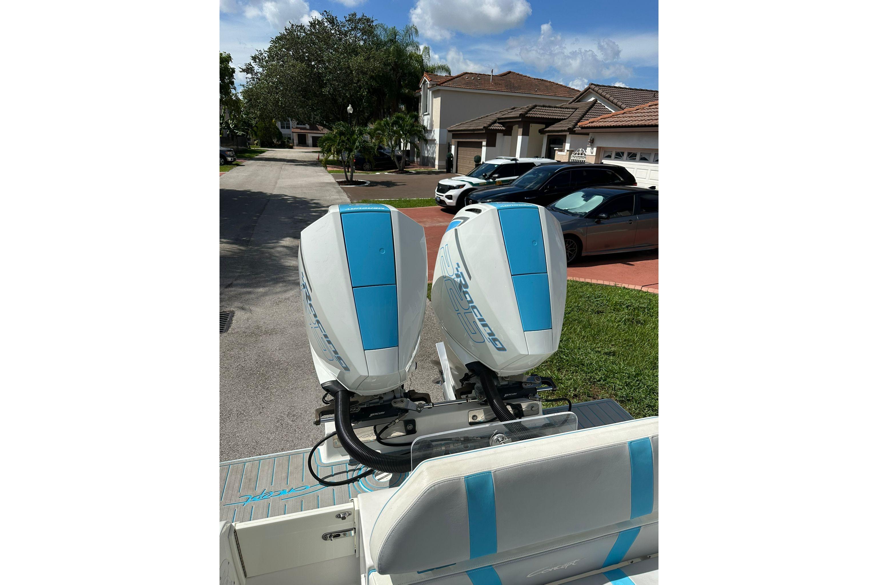 Twin outboard motors on a 2019 Concept 27' CC boat, parked in a residential area.