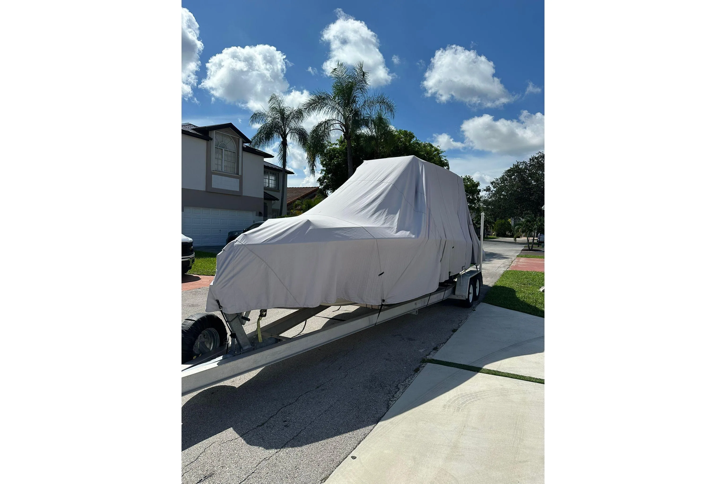 Covered 2019 Concept 27' CC boat on trailer in residential driveway.