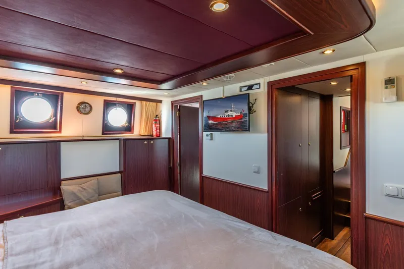 San Gottardo Yacht Photos Pics Luxurious 2009 Altena Expedition yacht cabin with wood paneling and porthole windows.