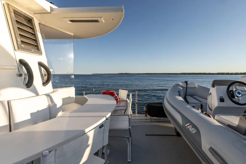 San Gottardo Yacht Photos Pics 2009 Altena Expedition yacht deck with seating and inflatable boat, overlooking calm sea.
