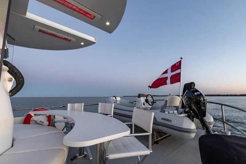 San Gottardo Yacht Photos Pics Luxurious 2009 Altena Expedition yacht deck with Danish flag and seating area at sunset.