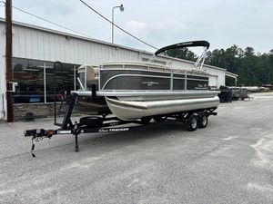 2025 Sun Tracker Party Barge 20 DLX pontoon boat on trailer, parked outside a building.