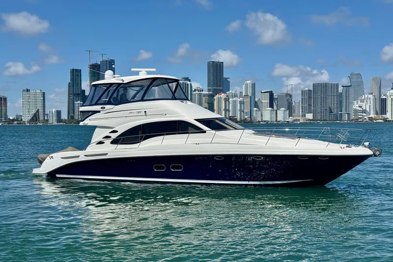 Ponchonchos Yacht Photos Pics 2005 Sea Ray 550 Sedan Bridge yacht cruising near city skyline on a sunny day.