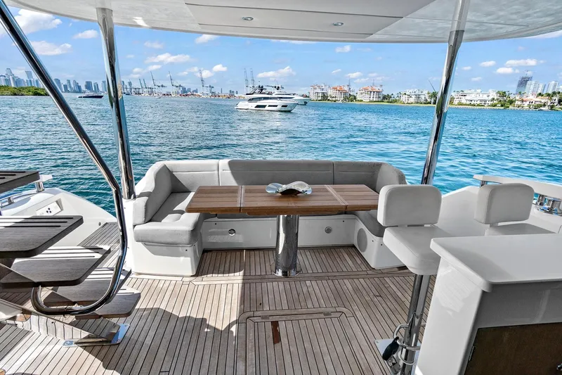 Exit Yacht Photos Pics Luxurious Sunseeker Manhattan 66 yacht deck with seating, overlooking serene blue waters.