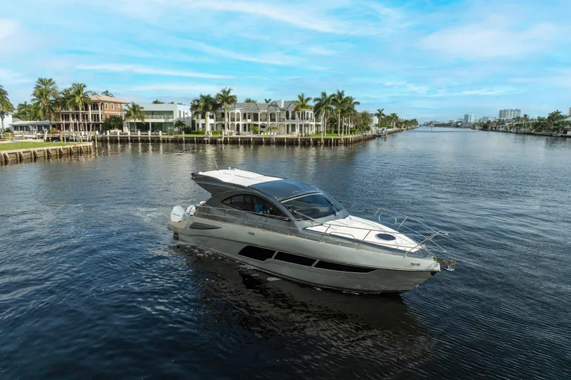  Yacht Photos Pics 2025 Valiatt 410HT yacht cruising on a scenic waterway with luxury homes in the background.