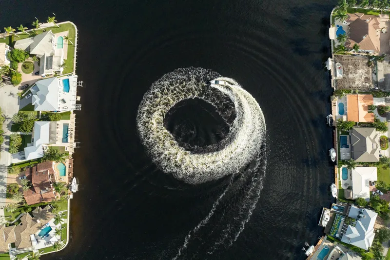  Yacht Photos Pics Aerial view of Valiatt 410HT boat creating circular wake in canal, surrounded by waterfront homes.
