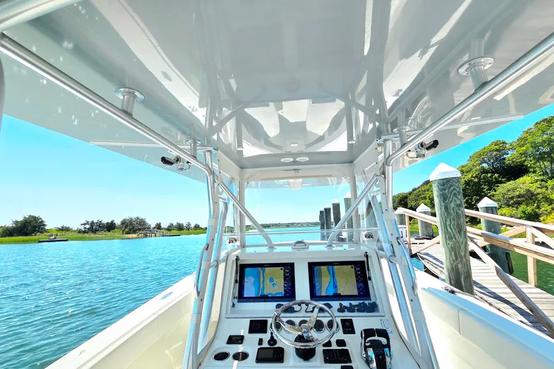 Impatient Yacht Photos Pics 2016 SeaVee 390Z boat cockpit with dual navigation screens, docked by a scenic waterway.