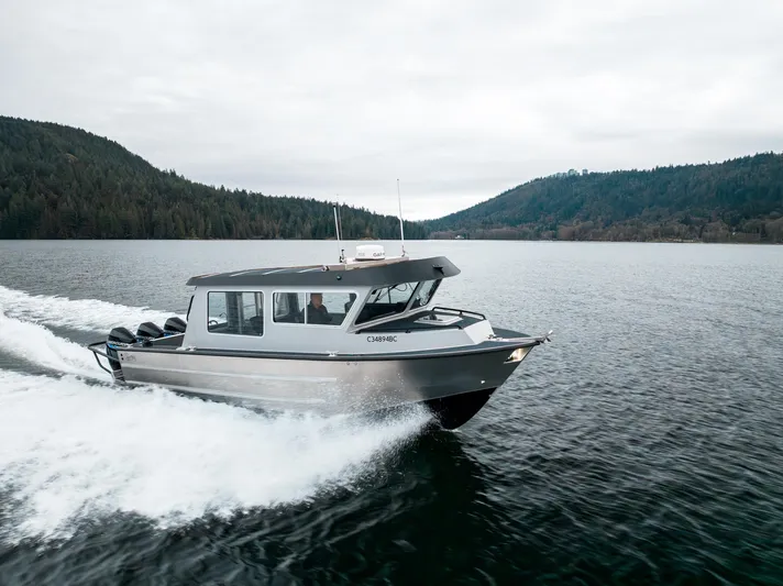  Yacht Photos Pics 2023 Liquid Metal Marine Maquinna Crew boat cruising on a serene lake with forested hills.