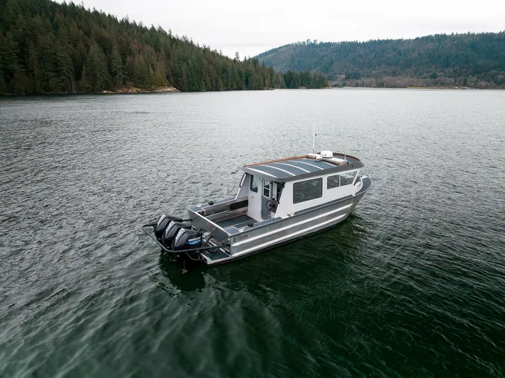  Yacht Photos Pics 2023 Liquid Metal Marine Maquinna Crew boat on a serene lake with forested shoreline.