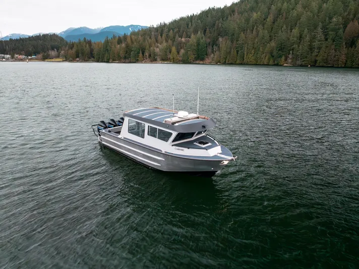  Yacht Photos Pics 2023 Liquid Metal Marine Maquinna Crew boat on a serene lake with forested backdrop.